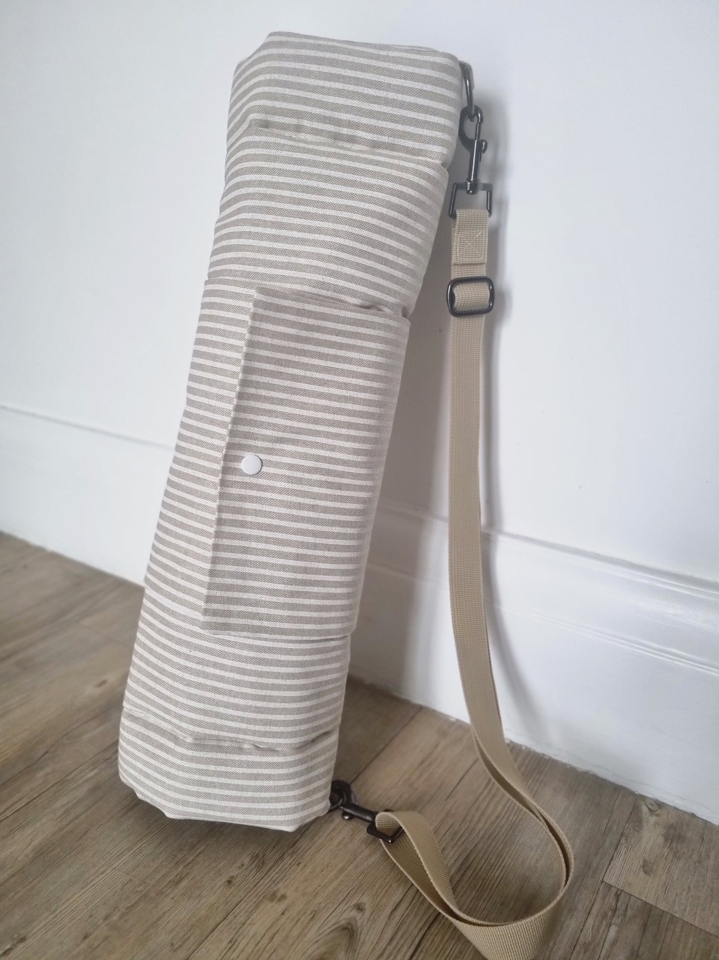 Neutral striped foldable dog settle mat with roll up fastening and strap to support with puppy settle training. This travel mat for dogs features a removable strap, a roll up fastening and a padded mat.