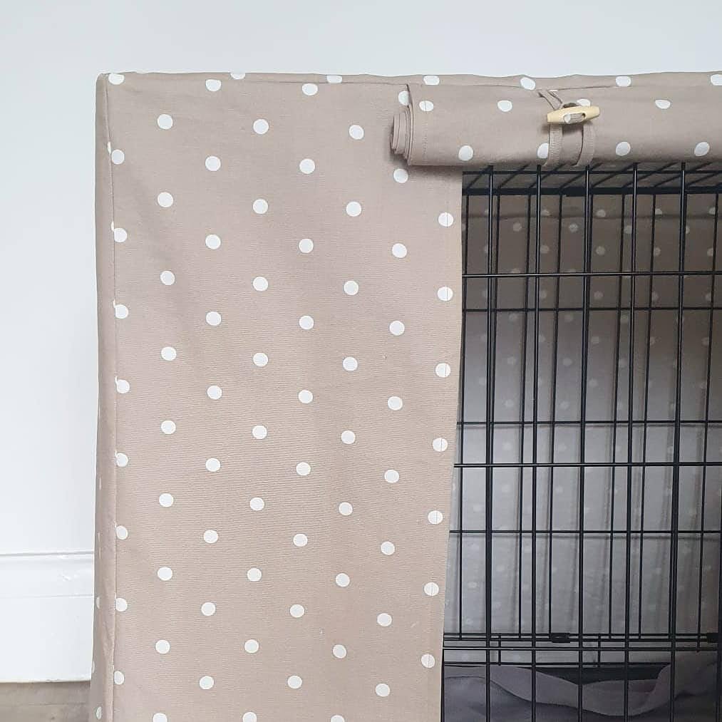 "A black wire dog crate covered with a custom fabric dog crate cover in a taupe spotty design. The aesthetic kennel cover features a minimalist design with a roll-up front panel.