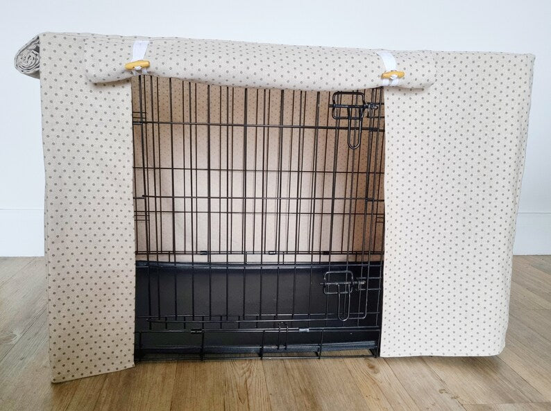 "A black wire dog crate covered with a custom fabric dog crate cover in a navy chequered design. The aesthetic kennel cover features a minimalist design with a roll-up front panel secured by white straps and wooden toggles, providing a cozy and stylish touch to the pet's space."