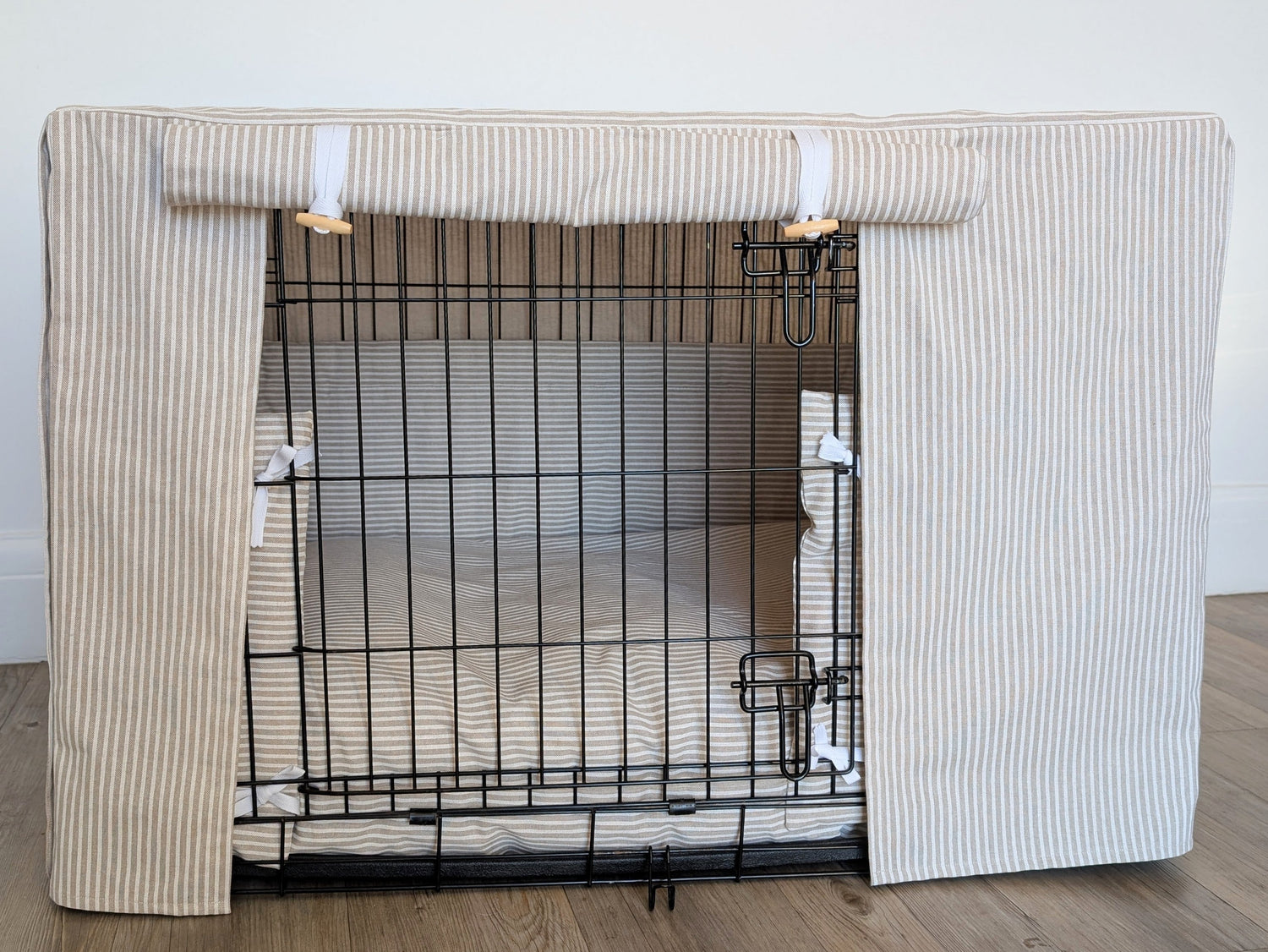 A dog crate cover made from fabric in a neutral striped design. Crate cover comes complete with a dog crate bumper and matching bed.