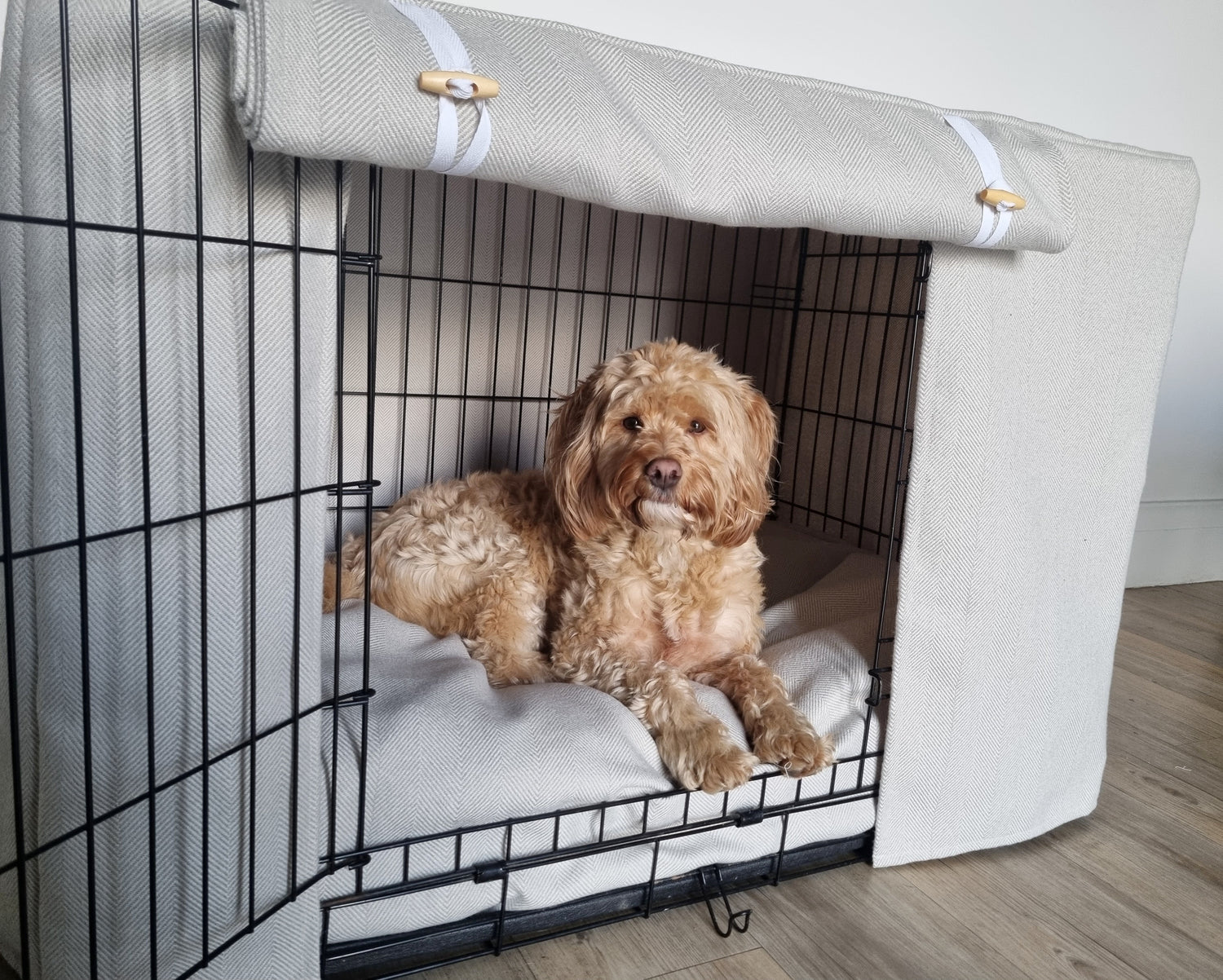 A dog crate cover made from fabric in a neutral striped design. Crate cover comes complete with a dog crate bumper and matching bed.