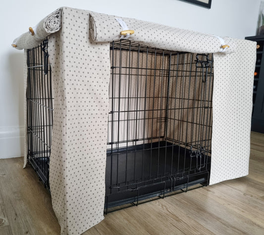 "A black wire dog crate covered with a custom fabric dog crate cover in a beige, neutral design. The aesthetic kennel cover features a minimalist design with a roll-up front panel secured by white straps and wooden toggles, providing a cozy and stylish touch to the pet's space."