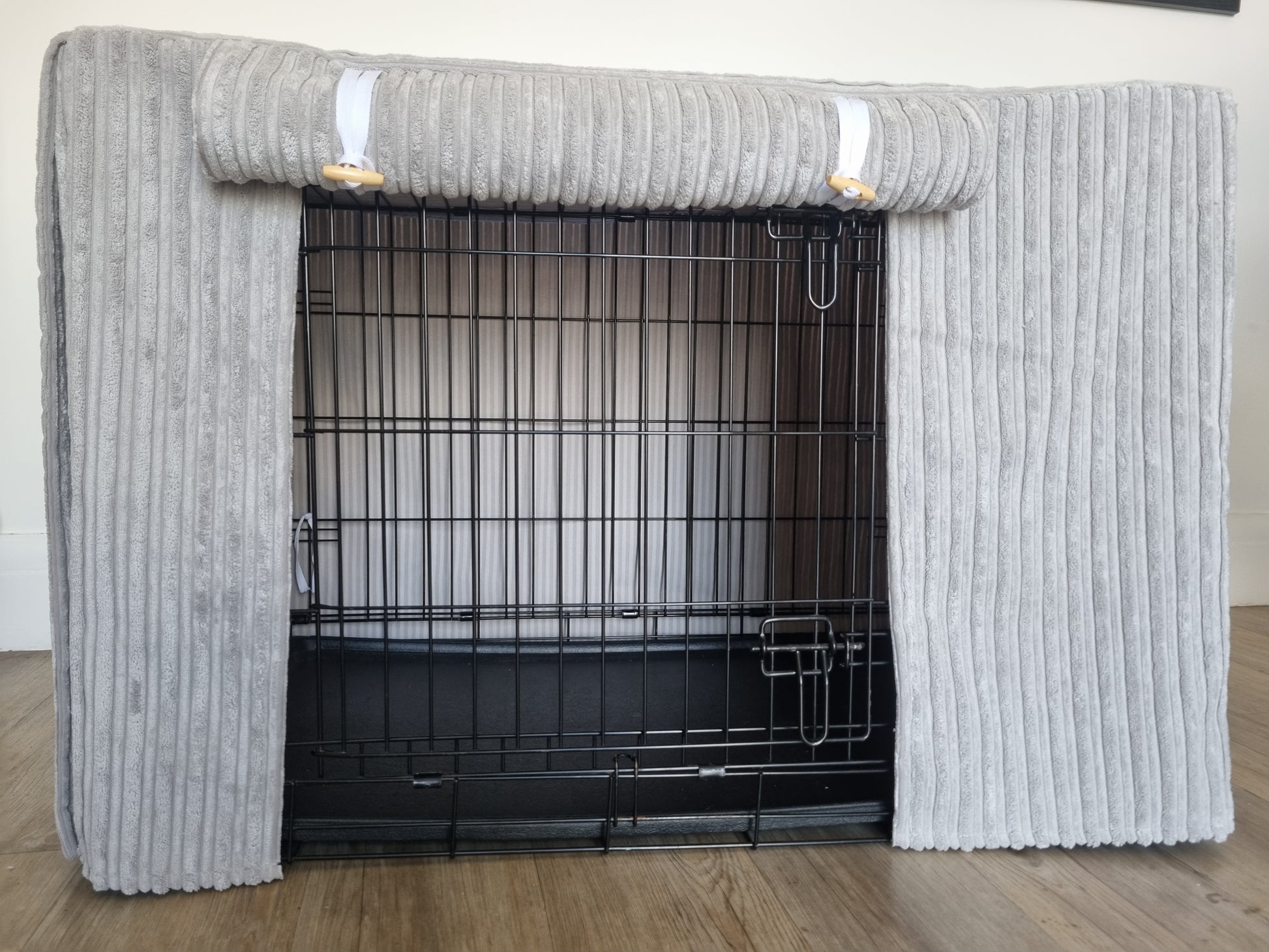 "A black wire dog crate covered with a custom fabric dog crate cover in a grey soft plush design. The aesthetic kennel cover features a minimalist design with a roll-up front panel.