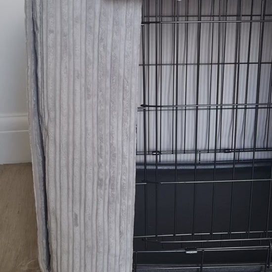 "A black wire dog crate covered with a custom fabric dog crate cover in a grey soft plush design. The aesthetic kennel cover features a minimalist design with a roll-up front panel.