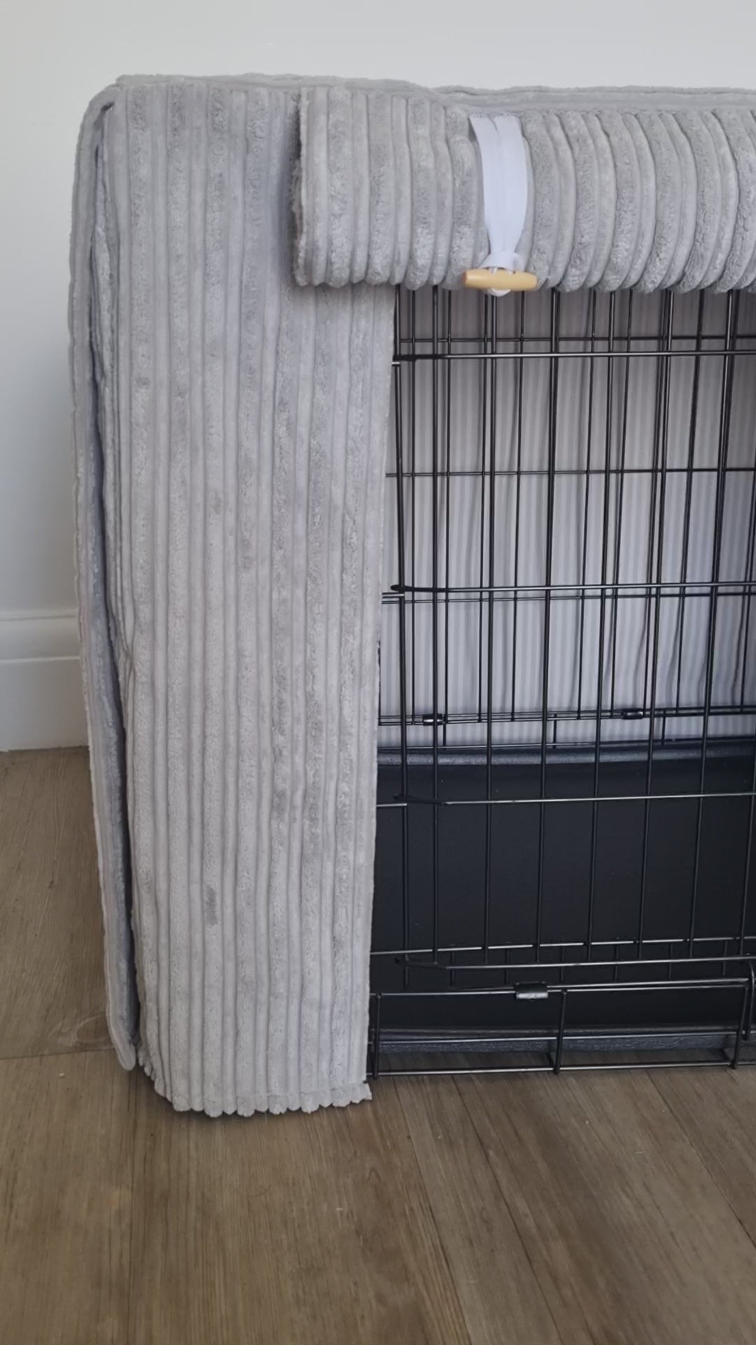 "A black wire dog crate covered with a custom fabric dog crate cover in a grey soft plush design. The aesthetic kennel cover features a minimalist design with a roll-up front panel.